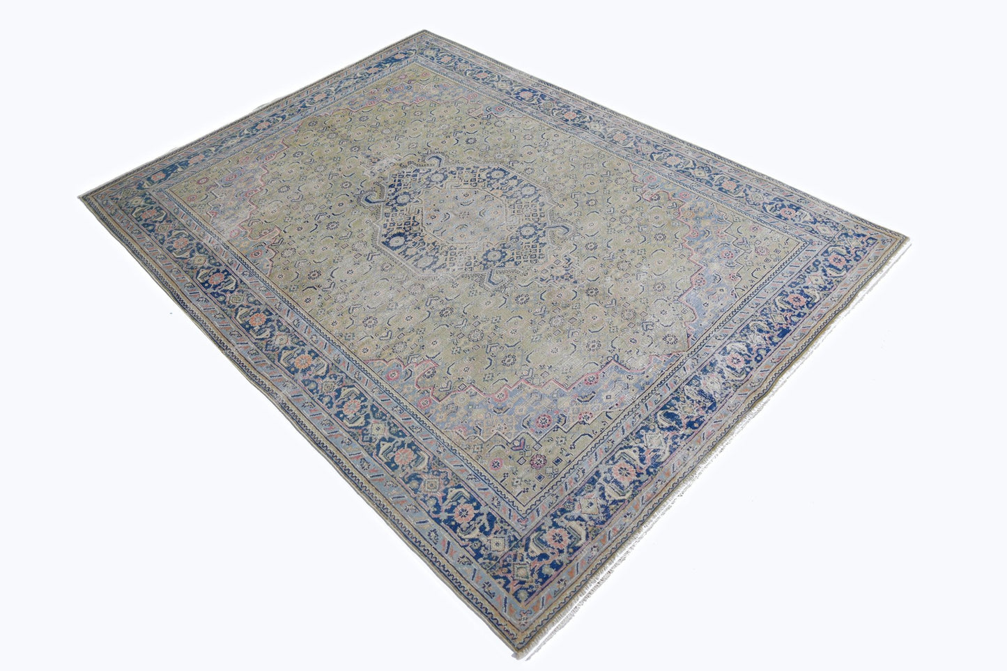 A vintage Persian Tabriz rug featuring a central medallion and intricate floral patterns in blue.