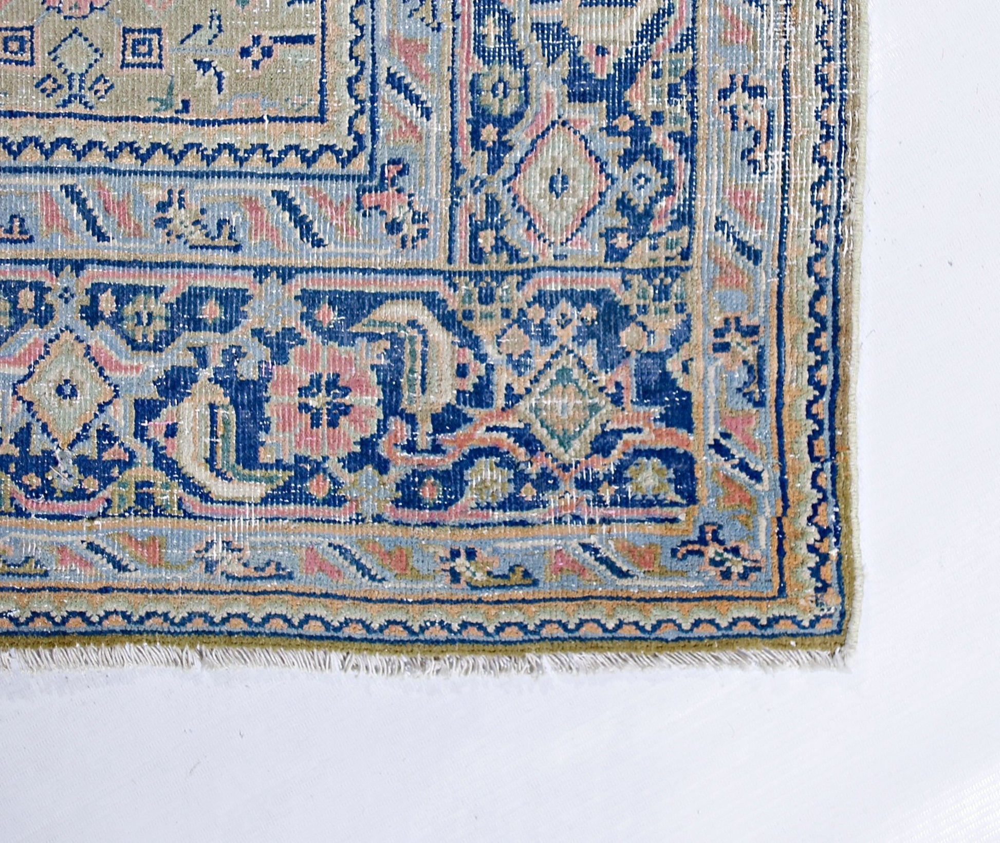 A vintage Persian Tabriz rug featuring intricate blue, pink, and cream geometric floral patterns.