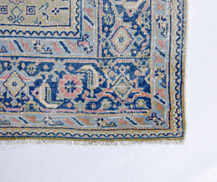 A vintage Persian Tabriz rug featuring intricate blue, pink, and cream geometric floral patterns.