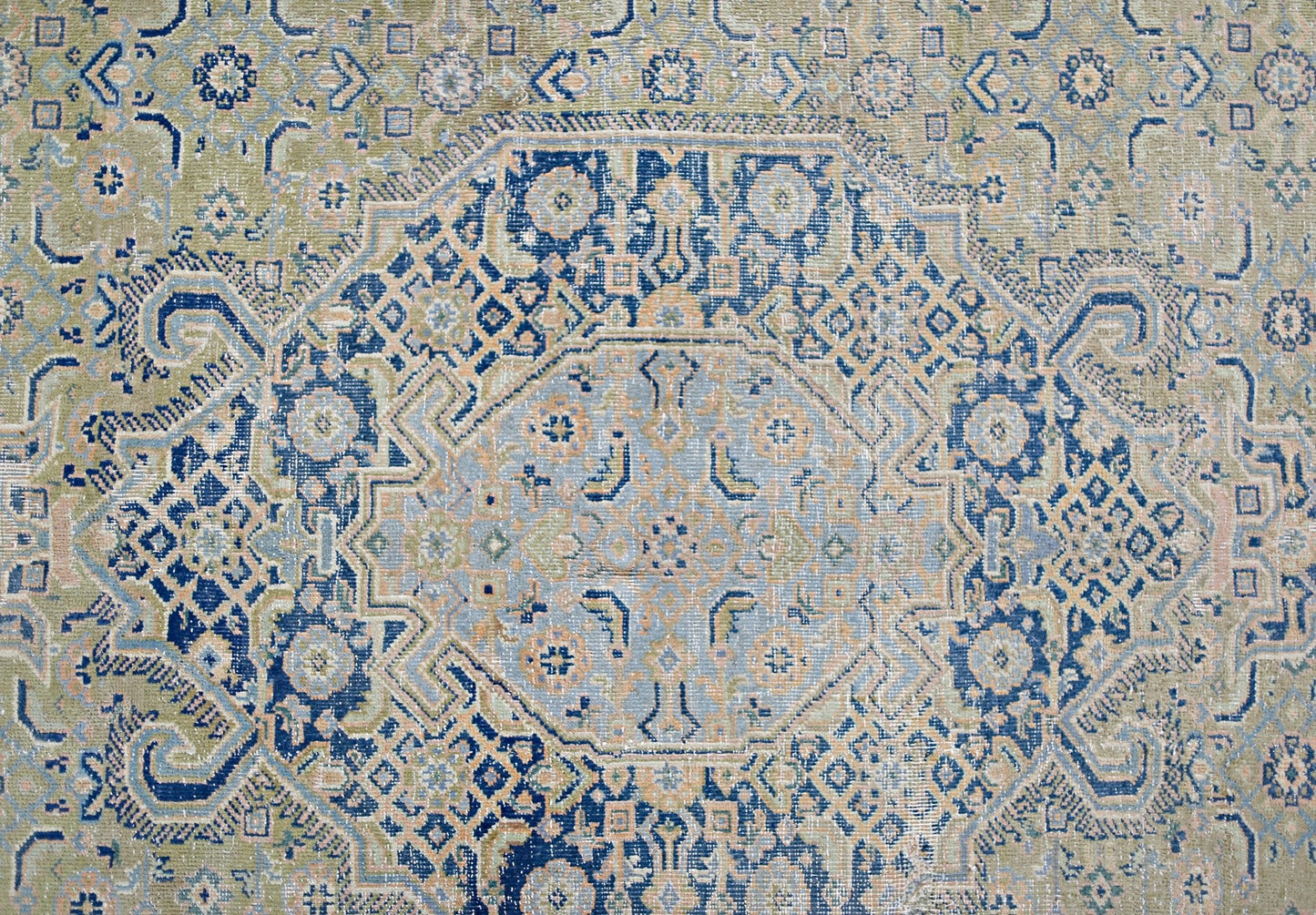 A vintage Persian Tabriz rug featuring an intricate blue and beige geometric medallion pattern.