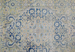 A vintage Persian Tabriz rug featuring an intricate blue and beige geometric medallion pattern.
