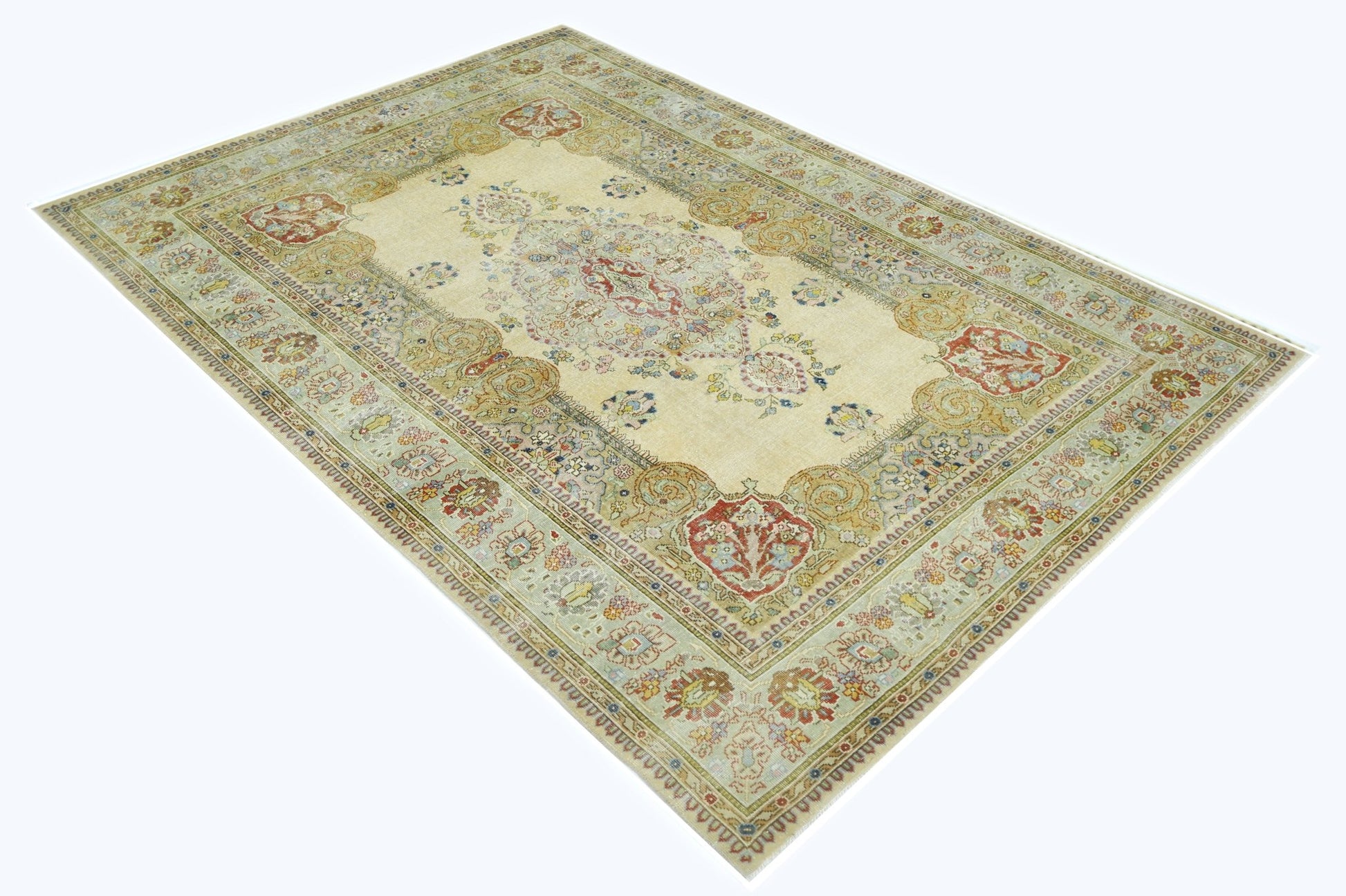 A vintage Persian Tabriz rug featuring a central floral medallion on a cream field.
