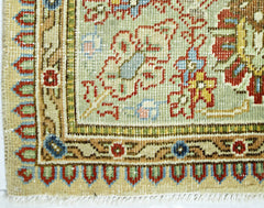 A close-up of a vintage Persian Tabriz rug featuring intricate floral patterns in red and blue.