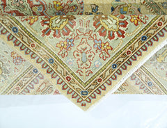 A corner of a vintage Persian Tabriz rug showing intricate floral patterns in red, blue, and gold.