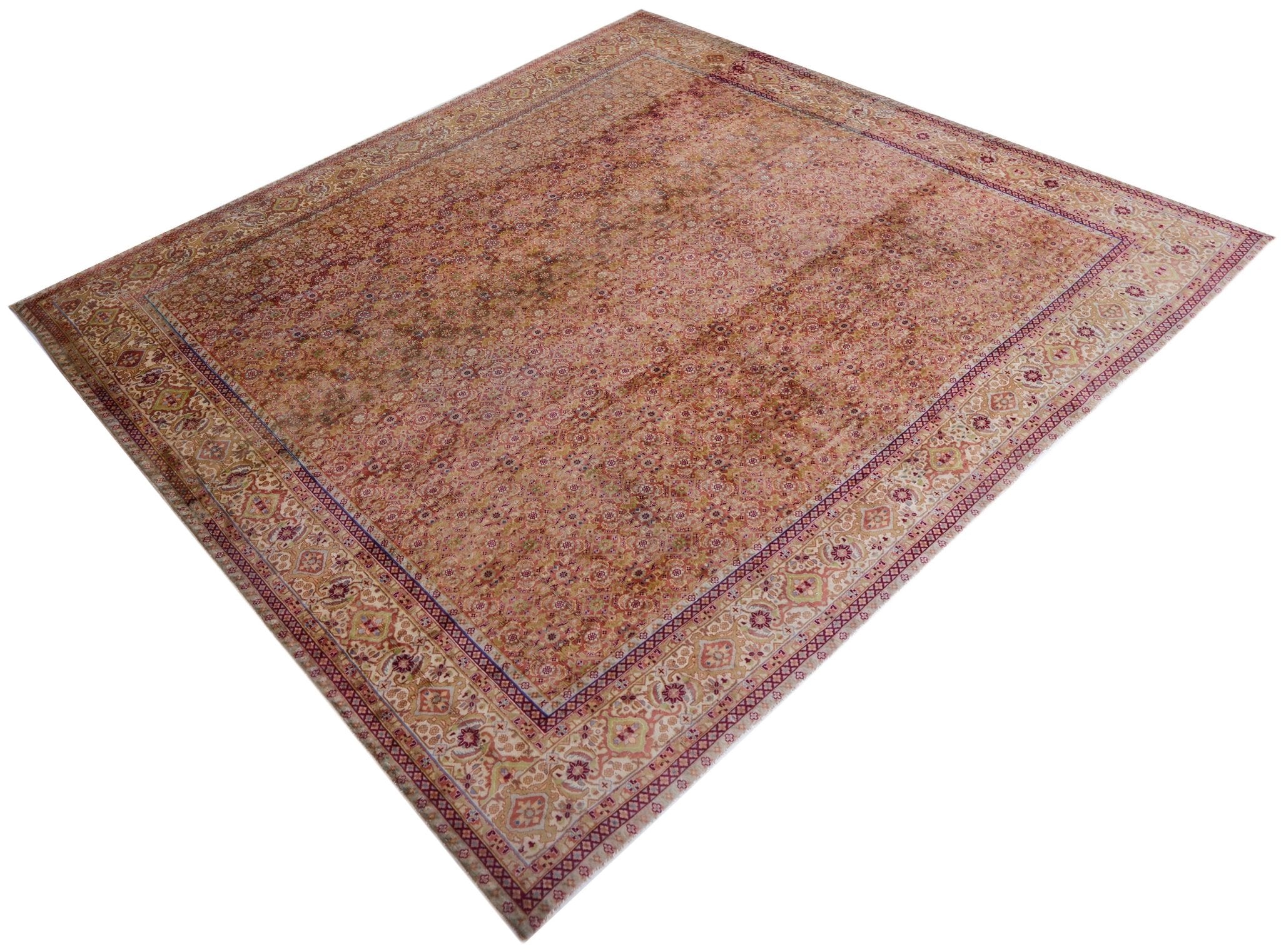 A vintage Persian Tabriz rug featuring an intricate floral pattern in warm, faded red tones.