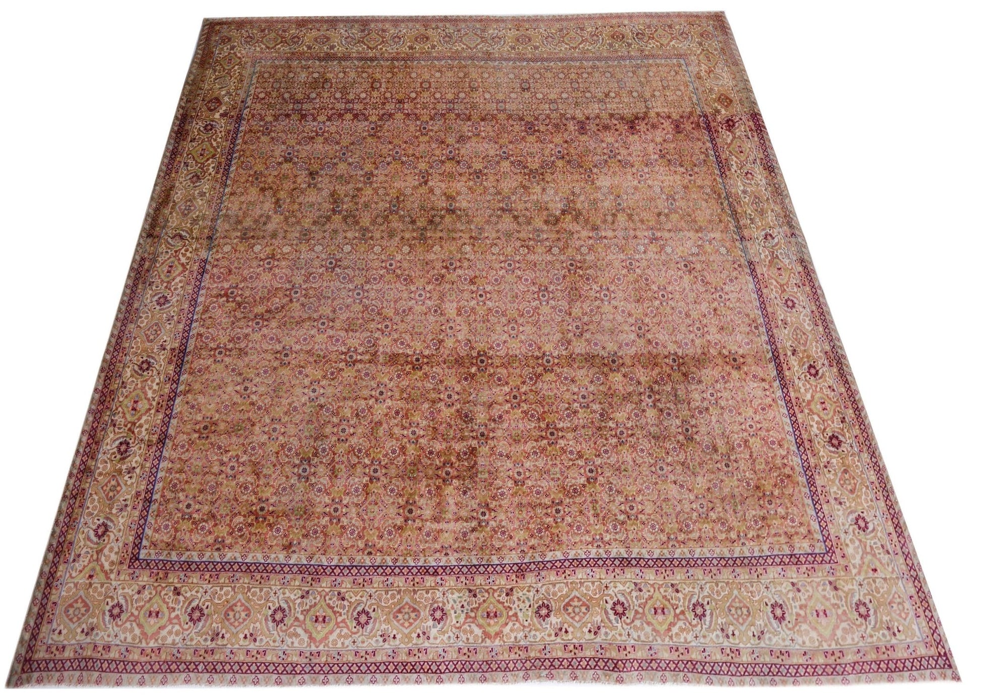 A vintage Persian Tabriz rug featuring an intricate floral pattern in soft, warm tones.
