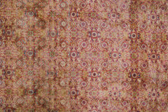 A vintage Persian Tabriz rug featuring an intricate, faded floral pattern in shades of red and gold.