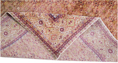 A vintage Persian Tabriz rug with a folded corner revealing its intricate floral medallion pattern.