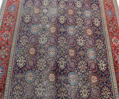 A vintage handwoven Persian Tabriz rug featuring a dense floral pattern in blue and red tones.