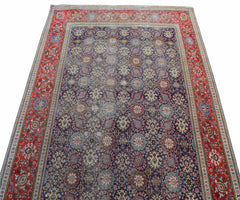 A vintage Persian Tabriz rug featuring a dark blue field with intricate floral patterns and red borders.