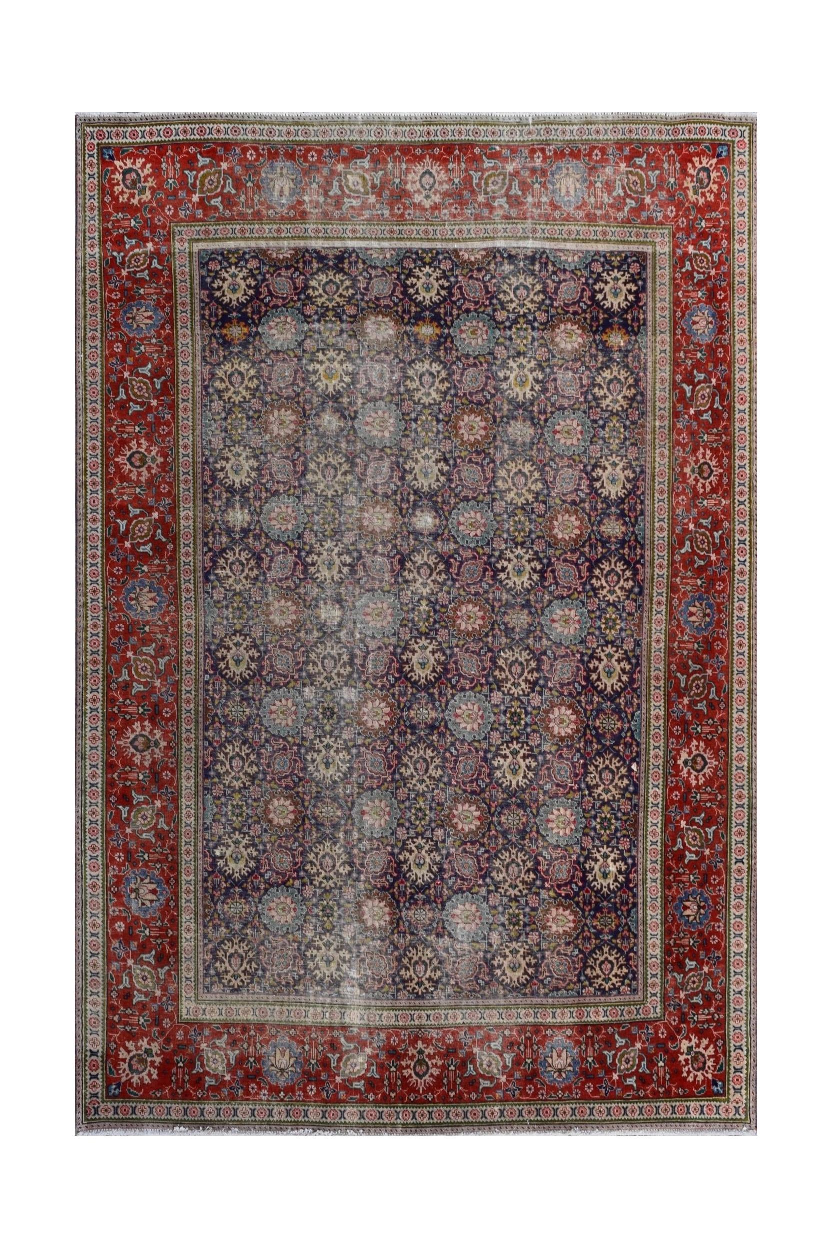 A vintage Persian Tabriz rug featuring a dark blue field with intricate floral patterns and red borders.