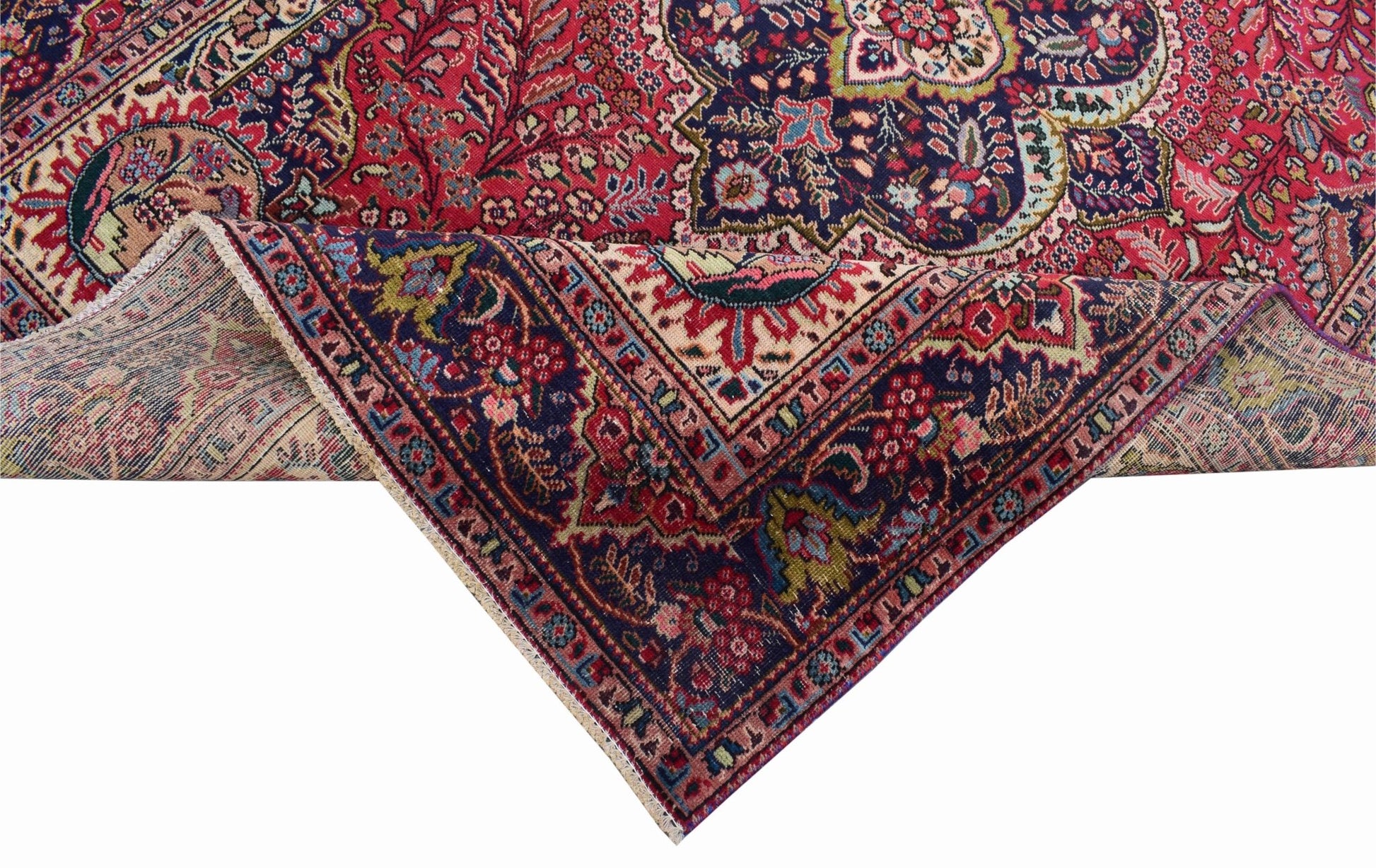 A vintage Persian Tabriz rug featuring a detailed floral medallion pattern in red and navy blue.
