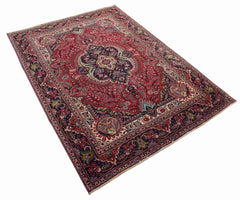 A vintage Persian Tabriz rug featuring a central medallion and intricate floral patterns in red.