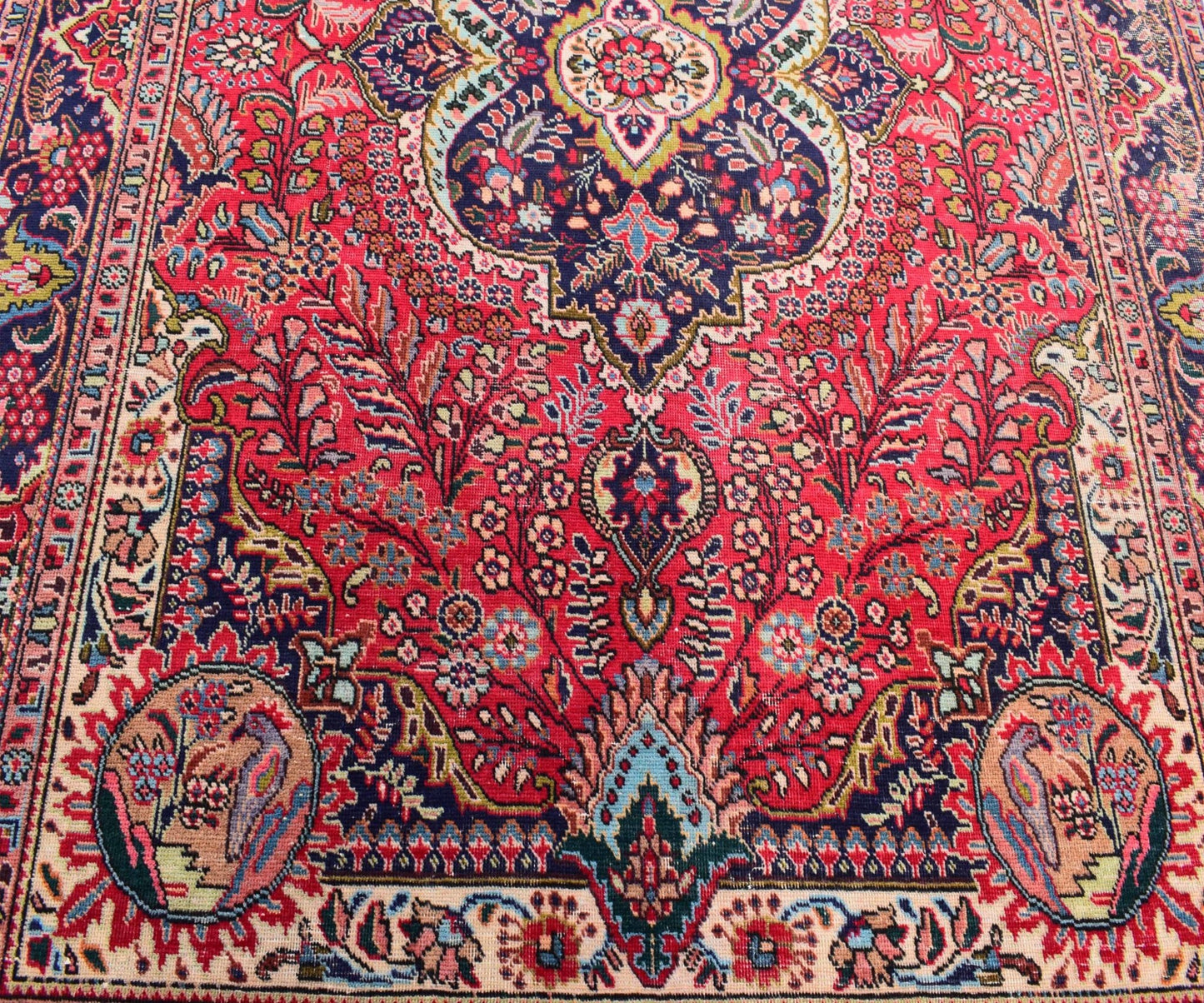 A vintage Persian Tabriz rug featuring an intricate floral medallion design in red and blue tones.