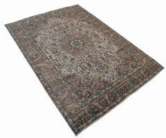 A vintage handwoven Persian Tabriz rug featuring intricate floral patterns in muted earth tones.