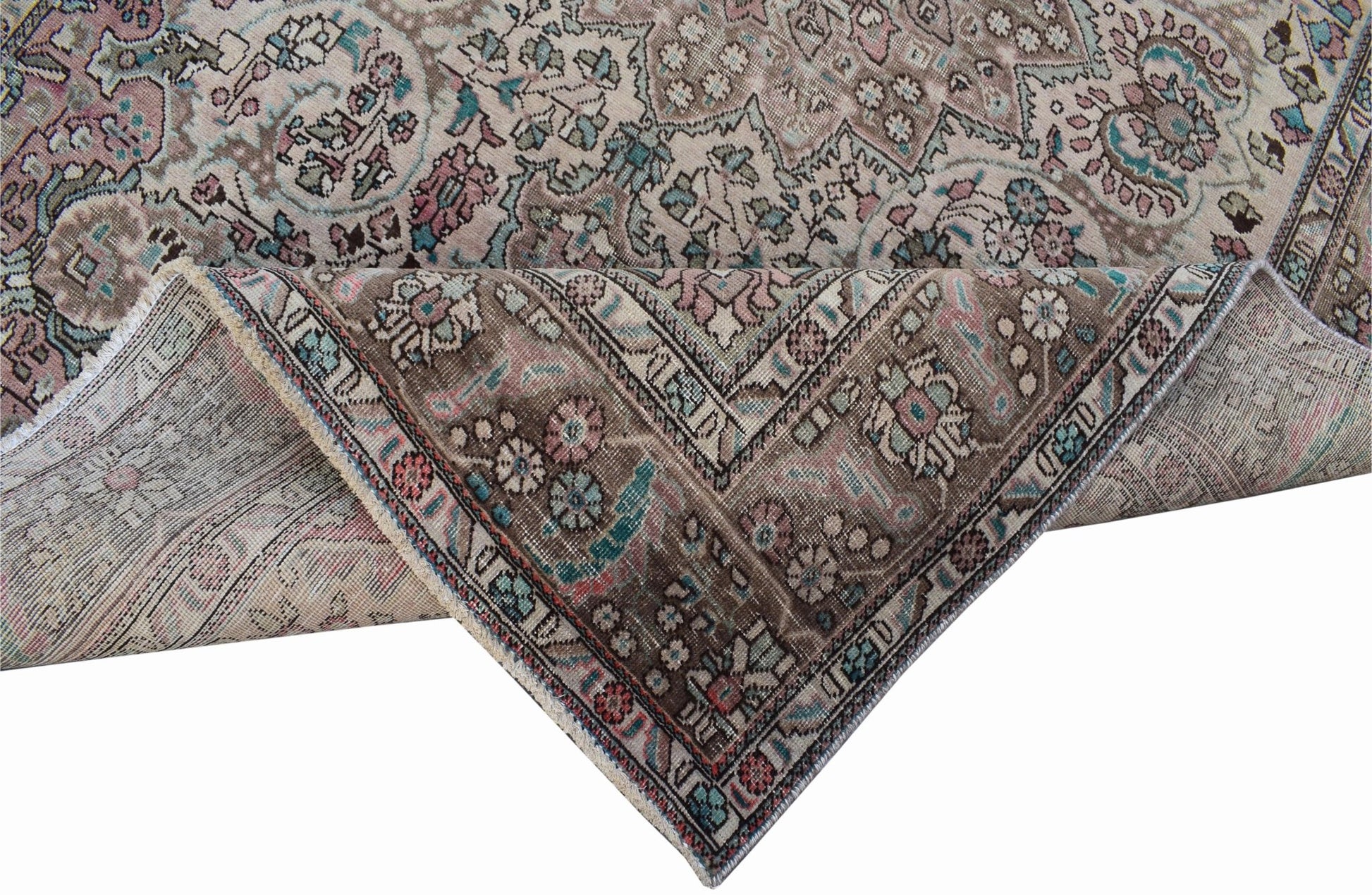 A vintage Persian Tabriz rug featuring intricate floral patterns in muted tones of pink and blue.