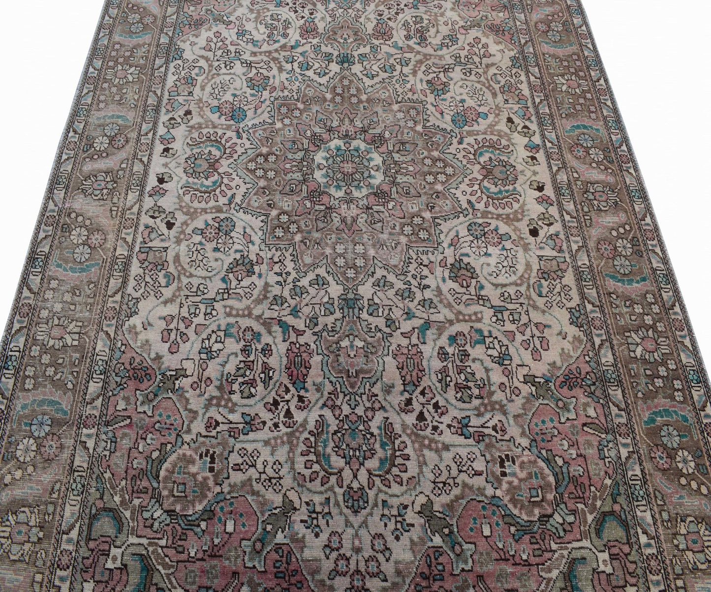 A vintage handwoven Persian Tabriz rug featuring intricate floral patterns in muted pink and blue.