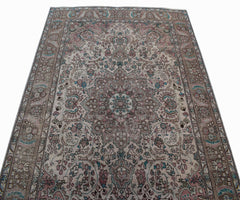A vintage handwoven Persian Tabriz rug featuring intricate floral patterns in muted earth tones.