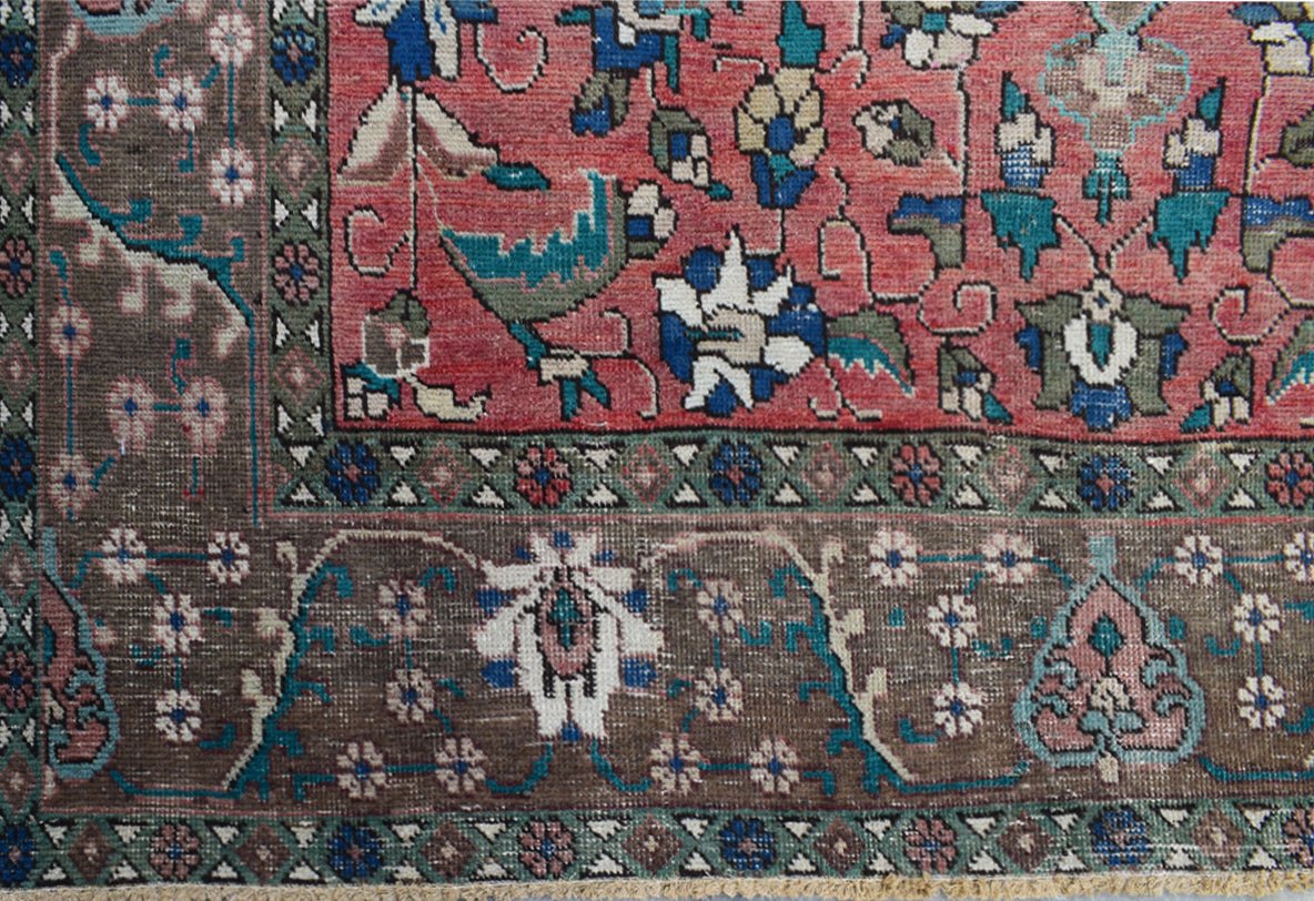 A vintage Persian Tabriz rug featuring intricate floral patterns in red, brown, and blue tones.