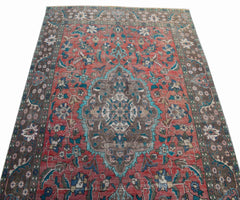 A vintage Persian Tabriz rug featuring a central medallion and intricate floral patterns in red.