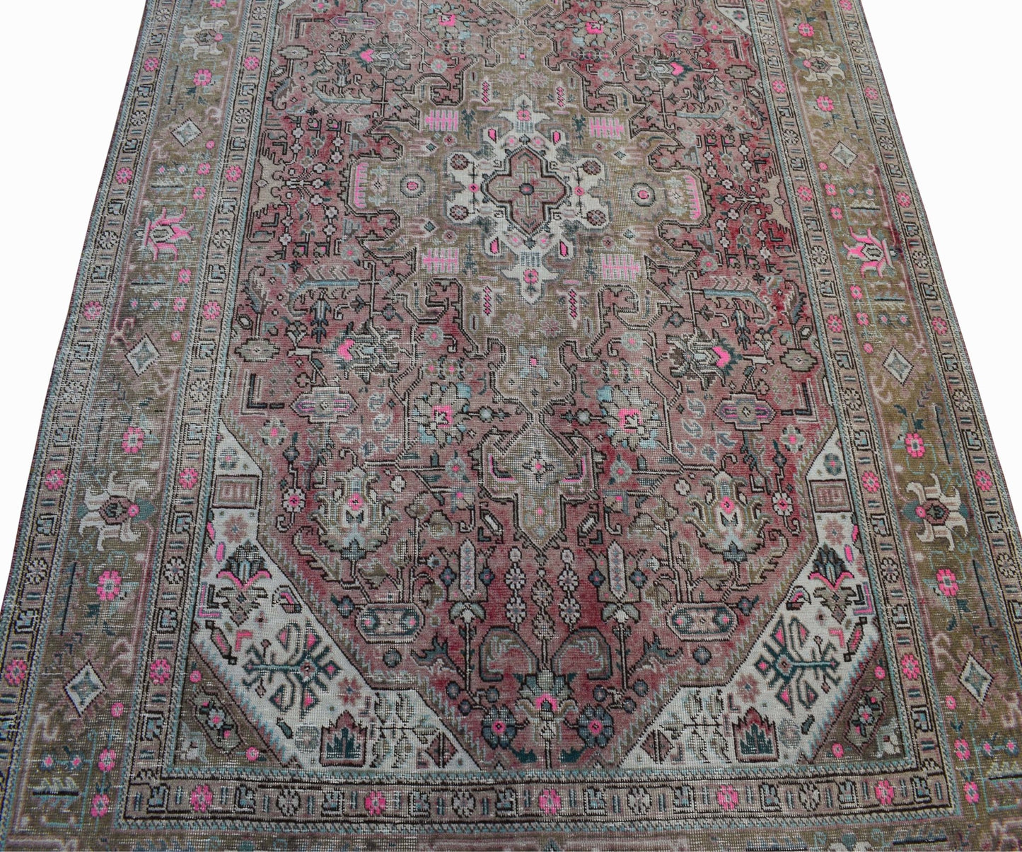A vintage handwoven Persian Tabriz rug featuring intricate floral patterns in pink and muted tones.