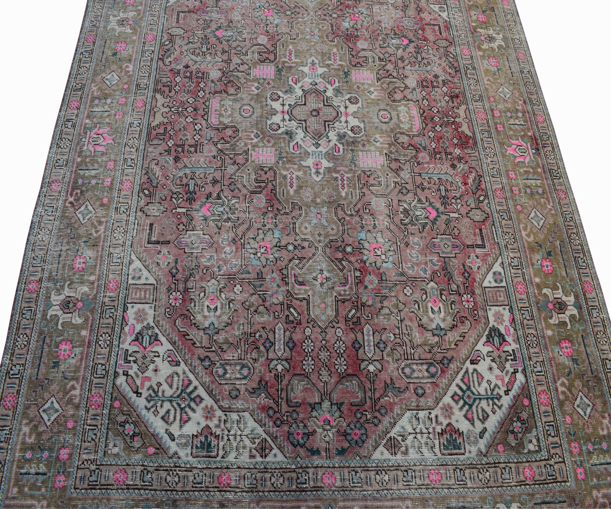 A vintage handwoven Persian Tabriz rug featuring intricate floral patterns in pink and muted tones.