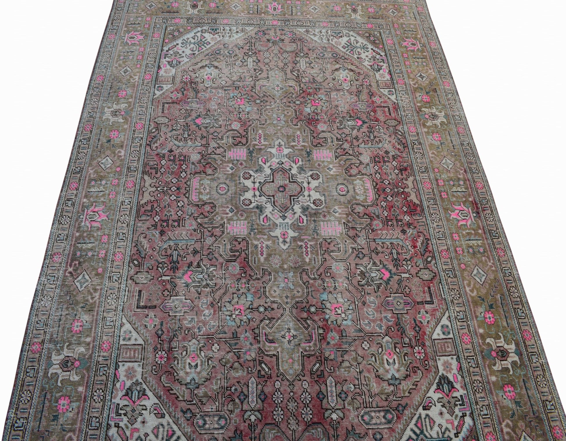 A vintage Persian Tabriz rug featuring intricate floral patterns in muted pink and brown tones.