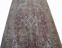 A vintage Persian Tabriz rug featuring intricate floral patterns in muted pink and brown tones.