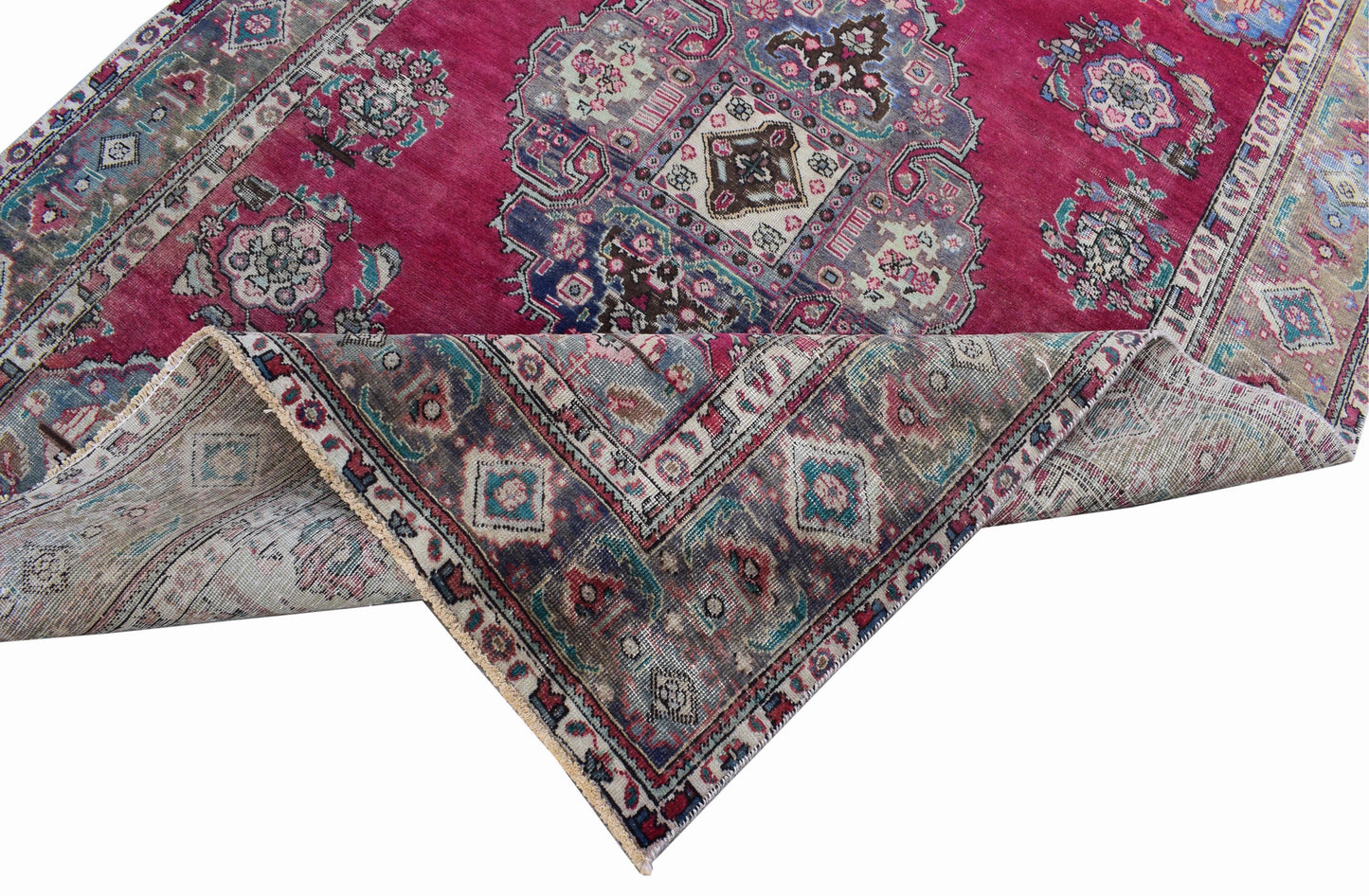 A vintage Persian Tabriz rug with a magenta field, central medallion, and intricate floral motifs.
