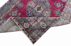A vintage Persian Tabriz rug with a magenta field, central medallion, and intricate floral motifs.