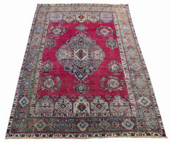 A vintage Persian Tabriz rug featuring a central medallion on a deep red field with floral motifs.