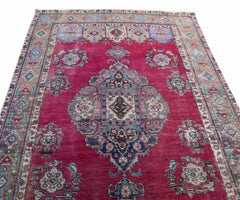 A vintage Persian Tabriz rug featuring a central medallion and intricate floral patterns in red.
