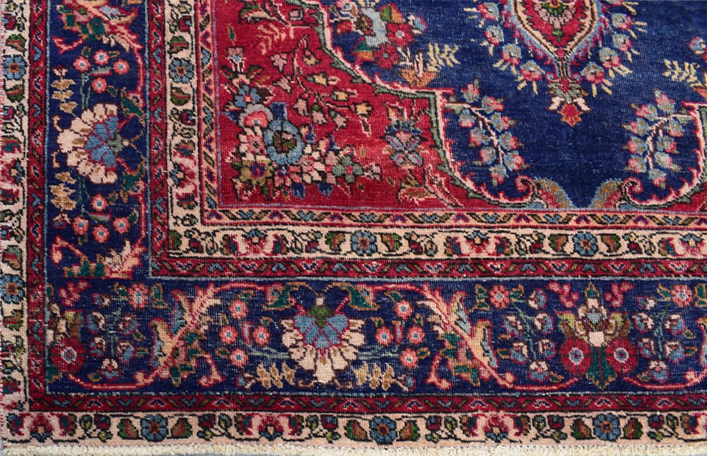 A vintage Persian Tabriz rug featuring an intricate floral pattern in blue and red tones.