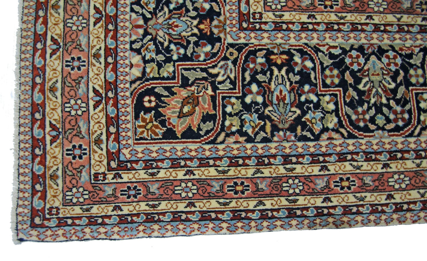 A vintage Persian Tabriz rug featuring intricate floral patterns in navy, pink, and cream.