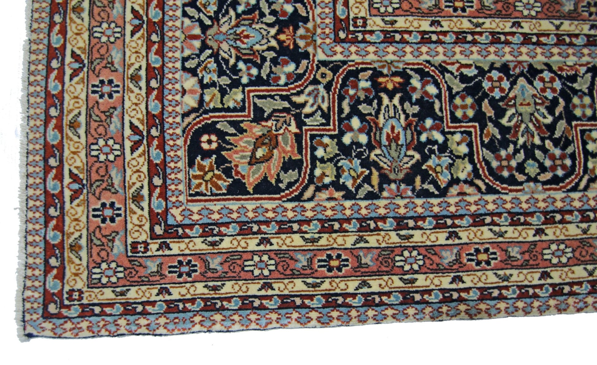 A vintage Persian Tabriz rug featuring intricate floral patterns in navy, pink, and cream.