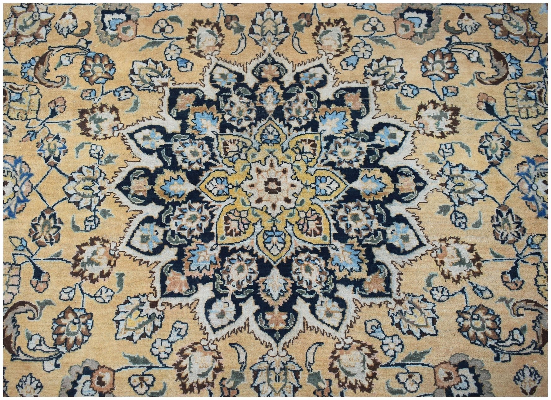A vintage Persian Kerman rug featuring an intricate floral medallion on a soft gold background.