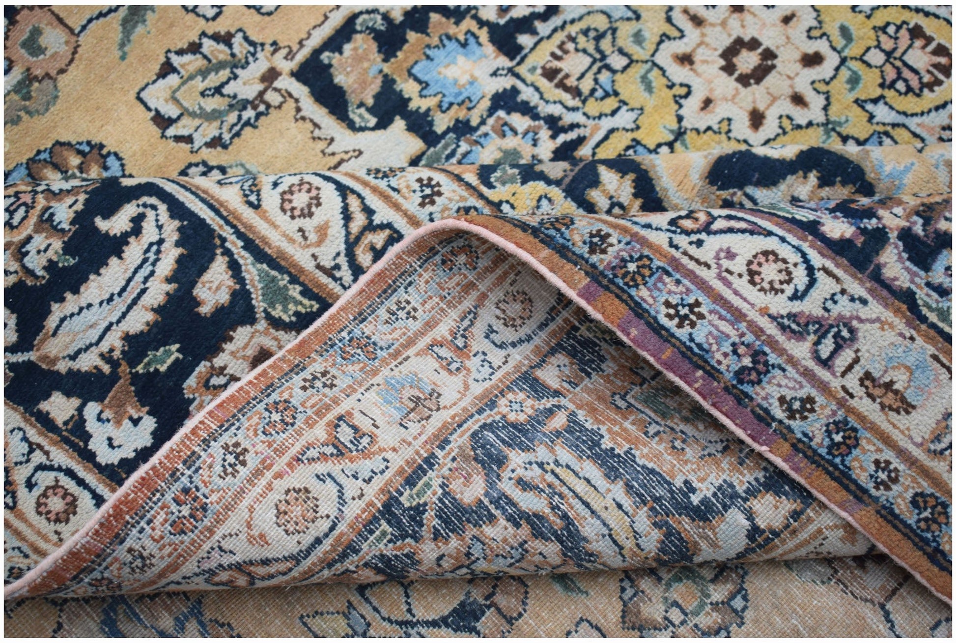 A vintage Persian Kerman rug featuring an intricate floral medallion design in blue and gold tones.