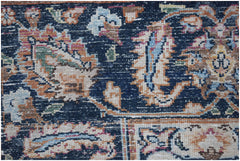 A close-up of a vintage Persian Kerman rug featuring intricate floral patterns on a dark blue field.