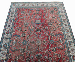 A vintage Persian Tabriz rug featuring a red field with intricate floral patterns and a medallion.