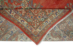 A corner of a vintage Persian Tabriz rug is folded back to reveal its intricate floral pattern.