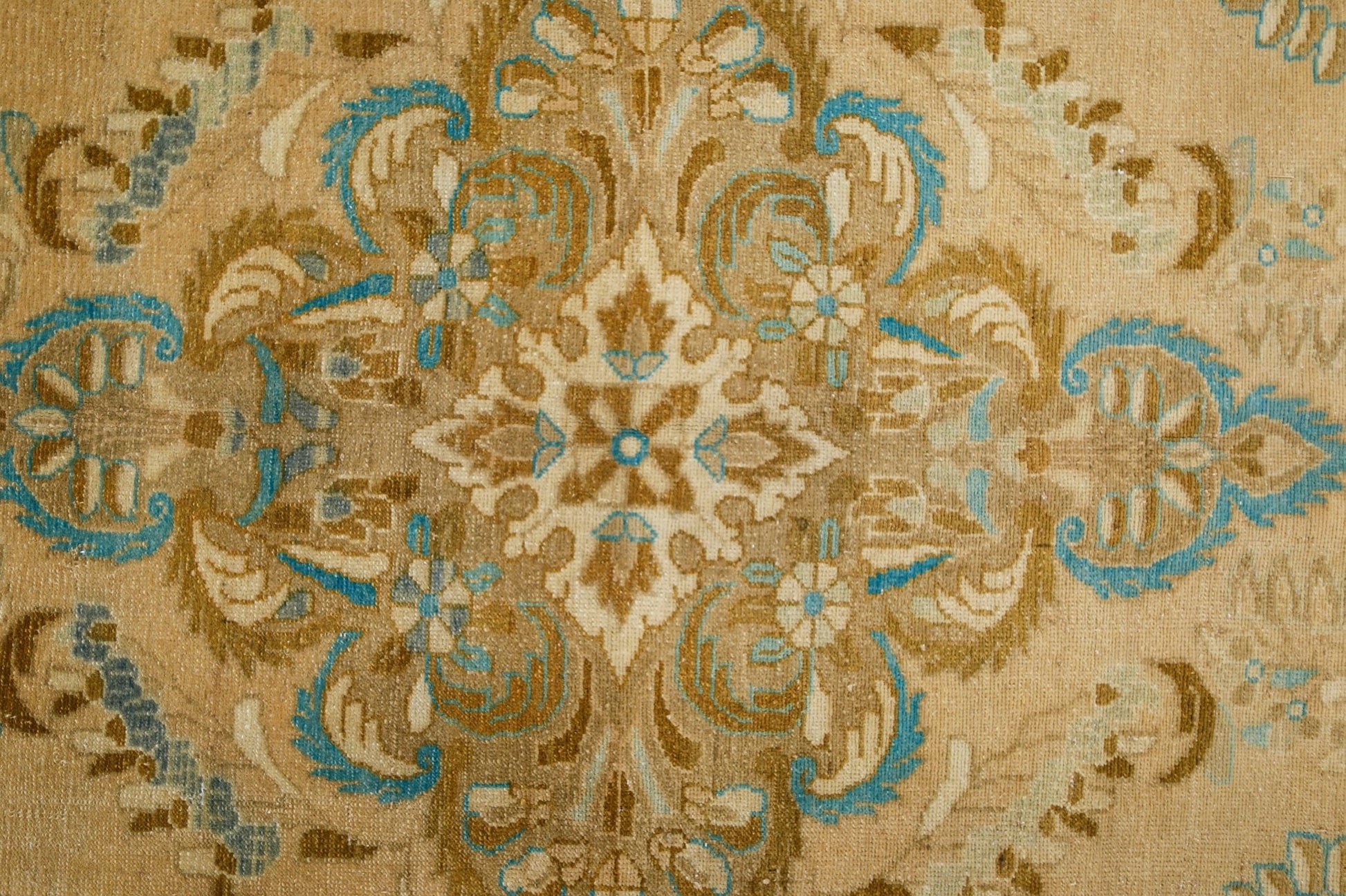 A vintage Persian Tabriz rug featuring a detailed floral medallion in blue and tan tones.