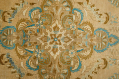 A vintage Persian Tabriz rug featuring a detailed floral medallion in blue and tan tones.
