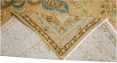 A vintage Persian Tabriz rug with a tan and blue floral pattern, shown folded to reveal its back.