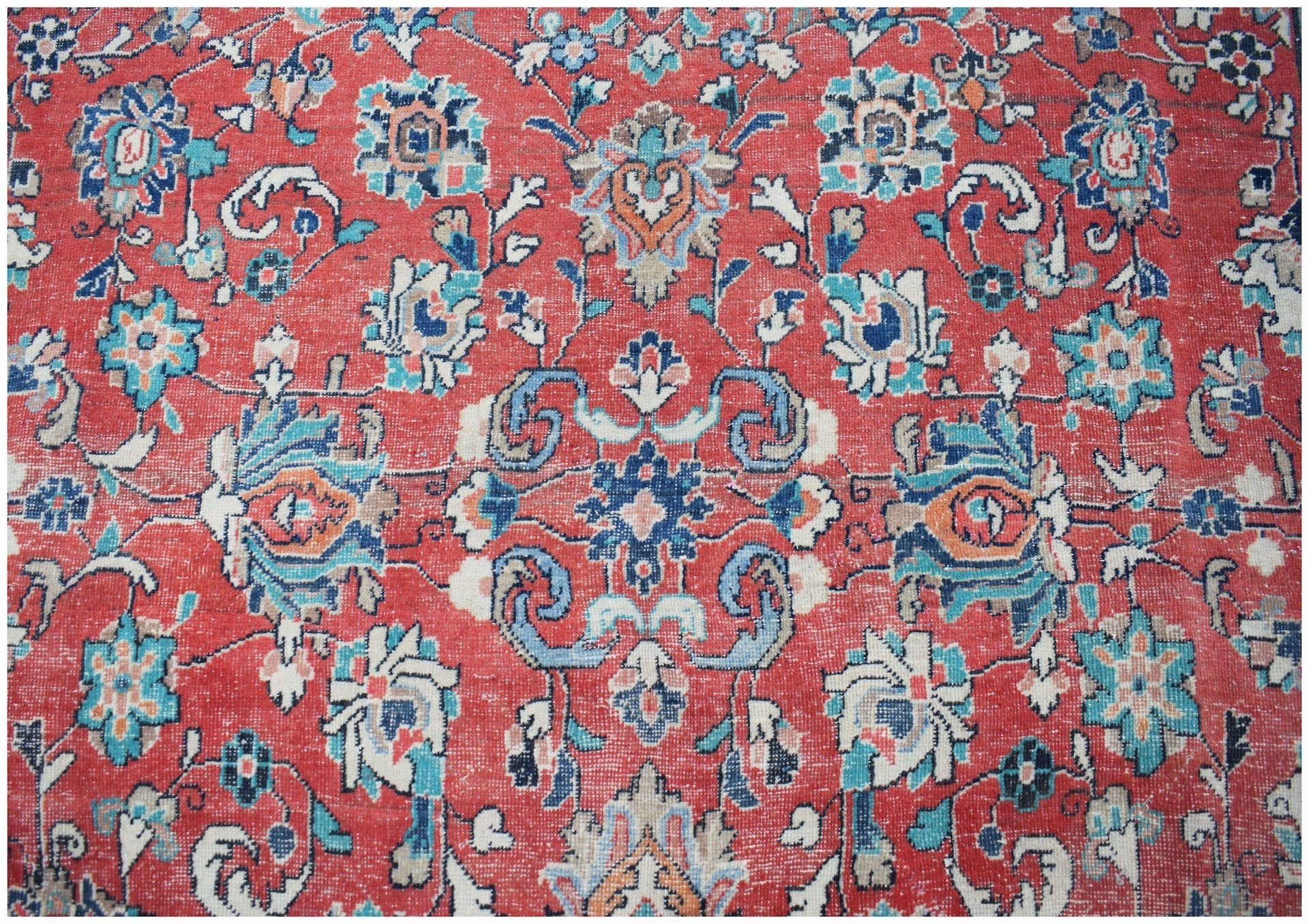 A vintage Persian Tabriz rug featuring intricate floral patterns in red, blue, and cream tones.