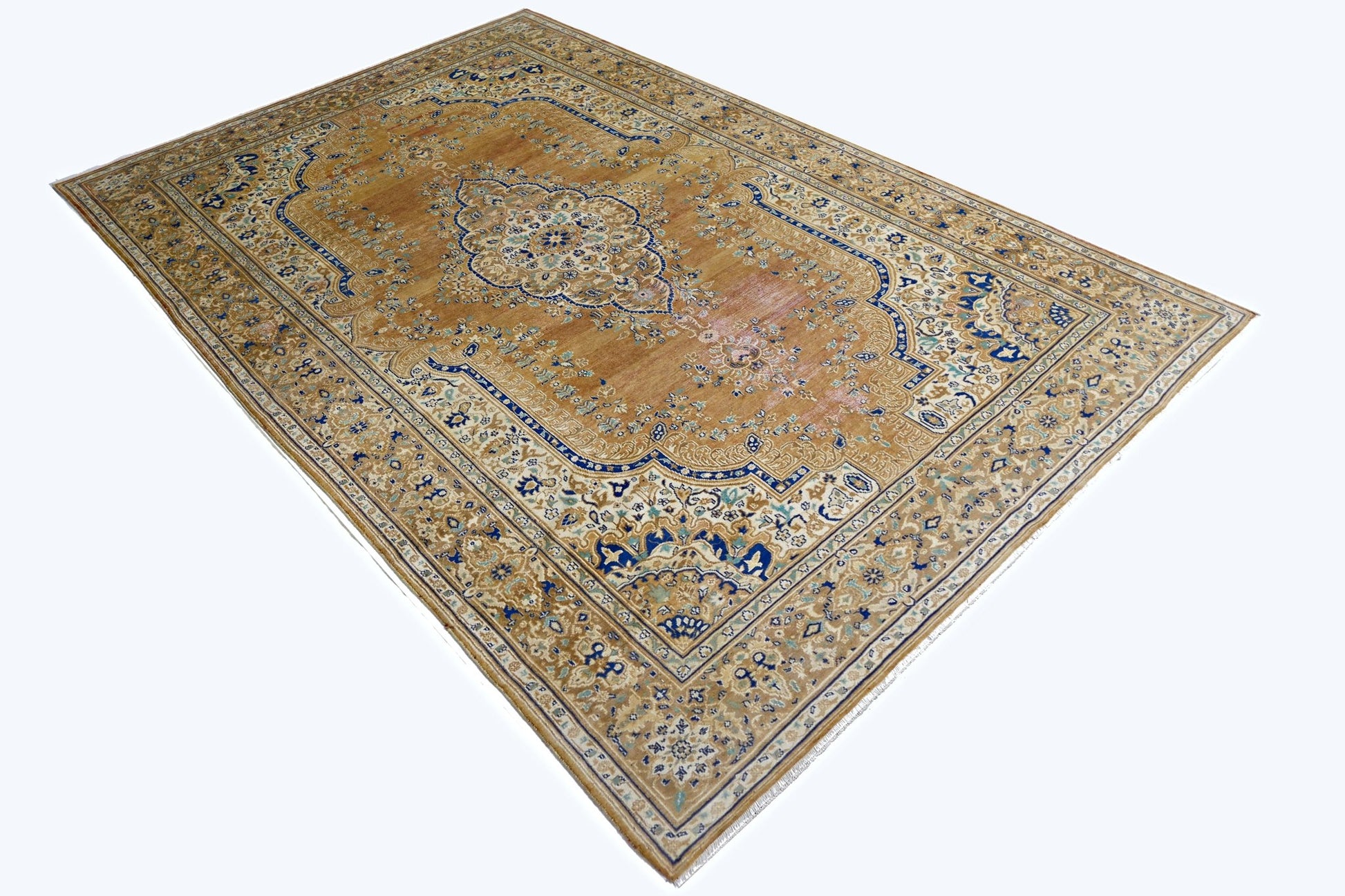 A vintage Persian Tabriz rug featuring a central medallion on a golden field with blue accents.
