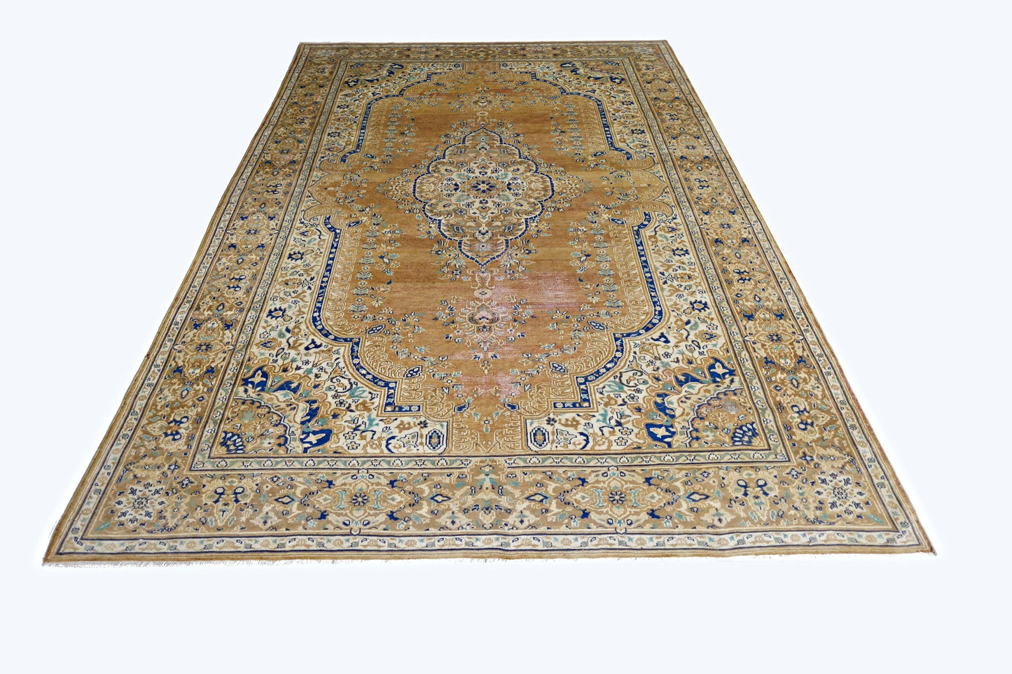 A vintage Persian Tabriz rug featuring a central medallion and intricate floral patterns in blue and tan.