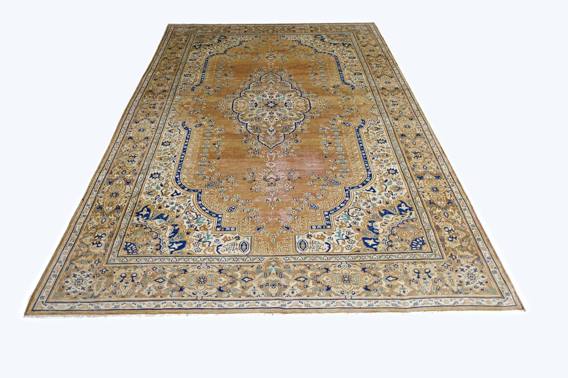 A vintage Persian Tabriz rug featuring a central medallion and intricate floral patterns in blue and tan.