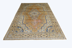 A vintage Persian Tabriz rug featuring a central medallion and intricate floral patterns in blue and tan.