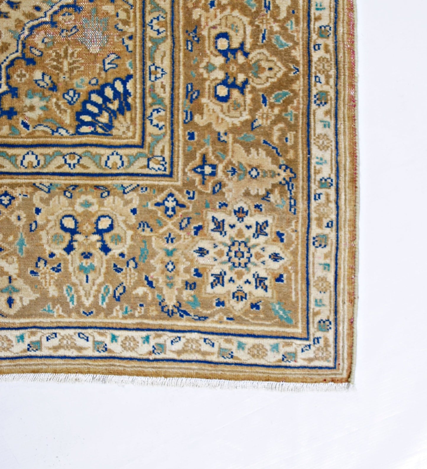 A vintage Persian Tabriz rug featuring intricate floral patterns in blue and beige tones.