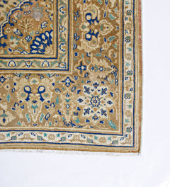 A vintage Persian Tabriz rug featuring intricate floral patterns in blue and beige tones.